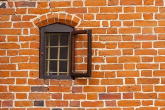 A small open window with a window grill on a gothic brick wall.Poland