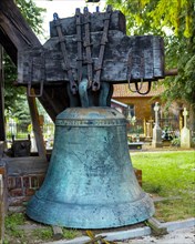 A belfry standing on the ground with four bells of different sizes in the village of Miloradz
