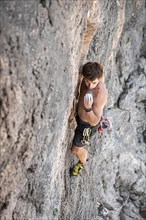Young man climbing on a rock face