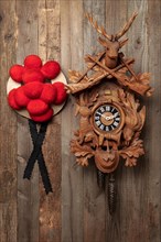 Original Black Forest cuckoo clock and Bollen hat in front of rustic wooden wall