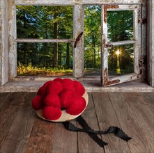 Old Black Forest Bollen hat in front of wooden window with view into the forest