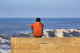 Young man sitting on the city wall