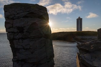 Basalt column and lighthouse in the backlight