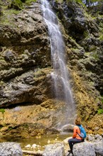Hiker in front of the Arzmoos waterfall