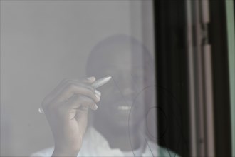 Young black man reconsiders a vision at the window with pen and great innovation