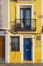 Close-up of blue door and balcony of yellow fishermen's houses in Villajoyosa