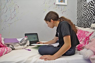 Girl accessing school work online at home using Microsoft Teams on laptop computer
