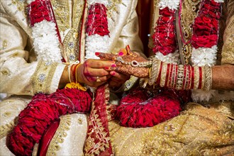 Indian groom passing wedding ring on his bride's finger on his wedding ceremony