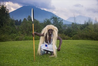 Man wears a wig carries a spear at a ceremony of former poachers