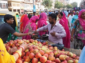 Vendor offering fresh apples at the market stall