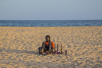 Souvenir seller sitting in the sand on the beach of Santa Maria