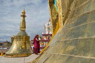 Tibetan Buddhist monk on new large painted and gilded stupa