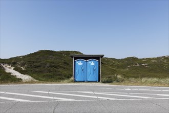 Two blue DIXI toilet stalls on a road