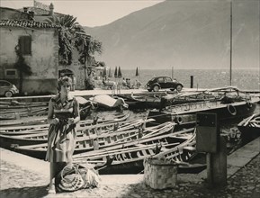 Lake Garda in 1960: young German tourist posing in front of fishing boats in the harbour
