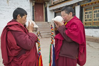 Buddhist nuns in the Terdom monastery call with the conch horn