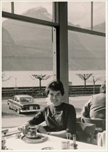 Young brunette woman sitting in a restaurant on Lake Lucerne with a glass of tea