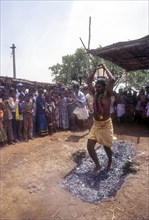 A man holding milk pot on head and walking on burning coal