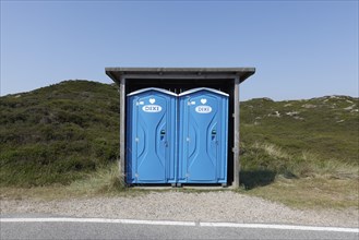 Two blue DIXI toilet stalls on a road