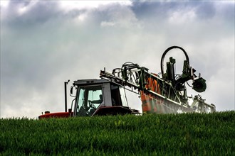 Tractor and wheat sprayer spraying in a field
