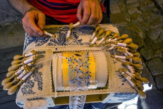 Man making traditional French lace before his shop