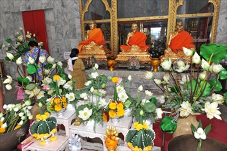 Flower offering in worship room with monk statues