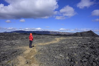 Woman looking across lava field of Krafla volcanic system towards a crater
