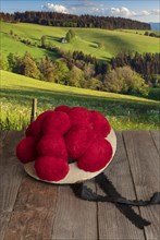 Black Forest Bollen hat on wooden table in front of hilly landscape