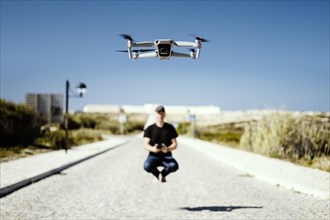 Man holding remote flying together with his drone in first plan