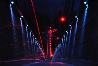 Pedestrian suspension bridge in the form of a rope bridge at night