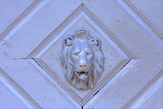 Lion's head as a door knocker on a gate