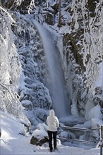 Hiker in front of an icy waterfall