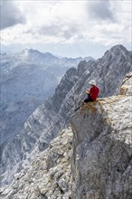 Hiker with helmet sitting on rocks