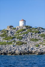 Old windmill on a rock with Greek flag