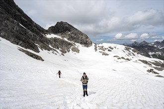 Hiker and hiker walking on old snow fields