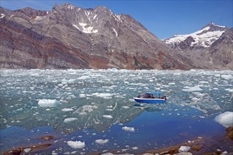 View of a blue small boat and a fjord filled with drift ice