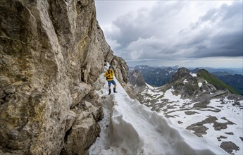 Hikers on snow remnants in rocky terrain