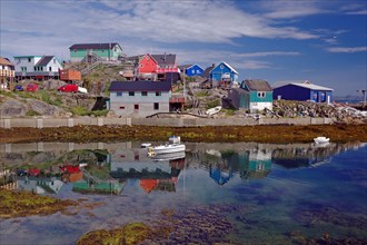 Colourful houses reflected in the still water of the fjord