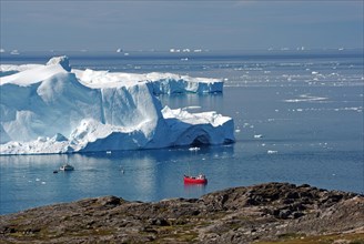 Red fishing boat in a bay with huge icebergs