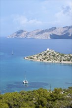 View of sailing boats and old windmill in Panormitis Bay