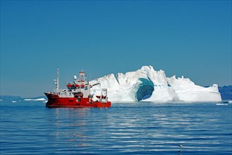 Red research vessel in front of iceberg with LOch