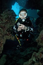 Young woman with scuba diving equipment dives into cave