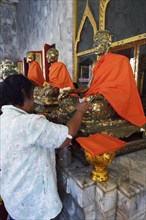 Believers paste statues of monks with gold leaf