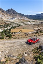 Tourists explore Nysiros with a red car on a gravel road