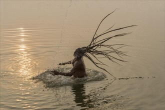 Rom Baba with water spraying from his flying dreadlocks in the river Ganges