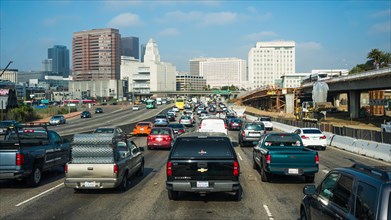 Cars on multi-lane urban highway in front of Los Angeles skyline