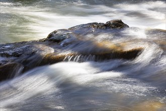Flowing water in a rocky stream bed with light reflections