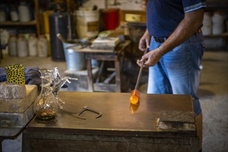 Working hot glass in the workshop of a glassblower