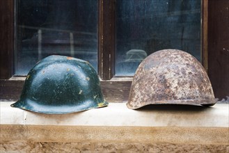 Soldiers' helmets displayed in front of a window