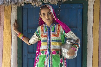 Girl in traditional dress standing in front of a house