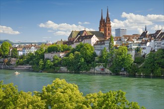 View of the Basel Cathedral in the middle of the old town of Basel with the turquoise Rhine River in the foreground